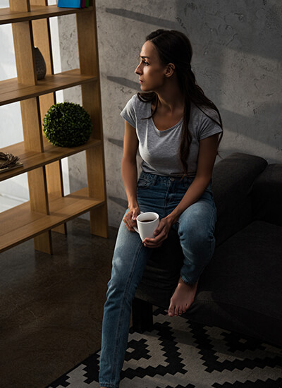 Depressed woman with coffee looking out of window